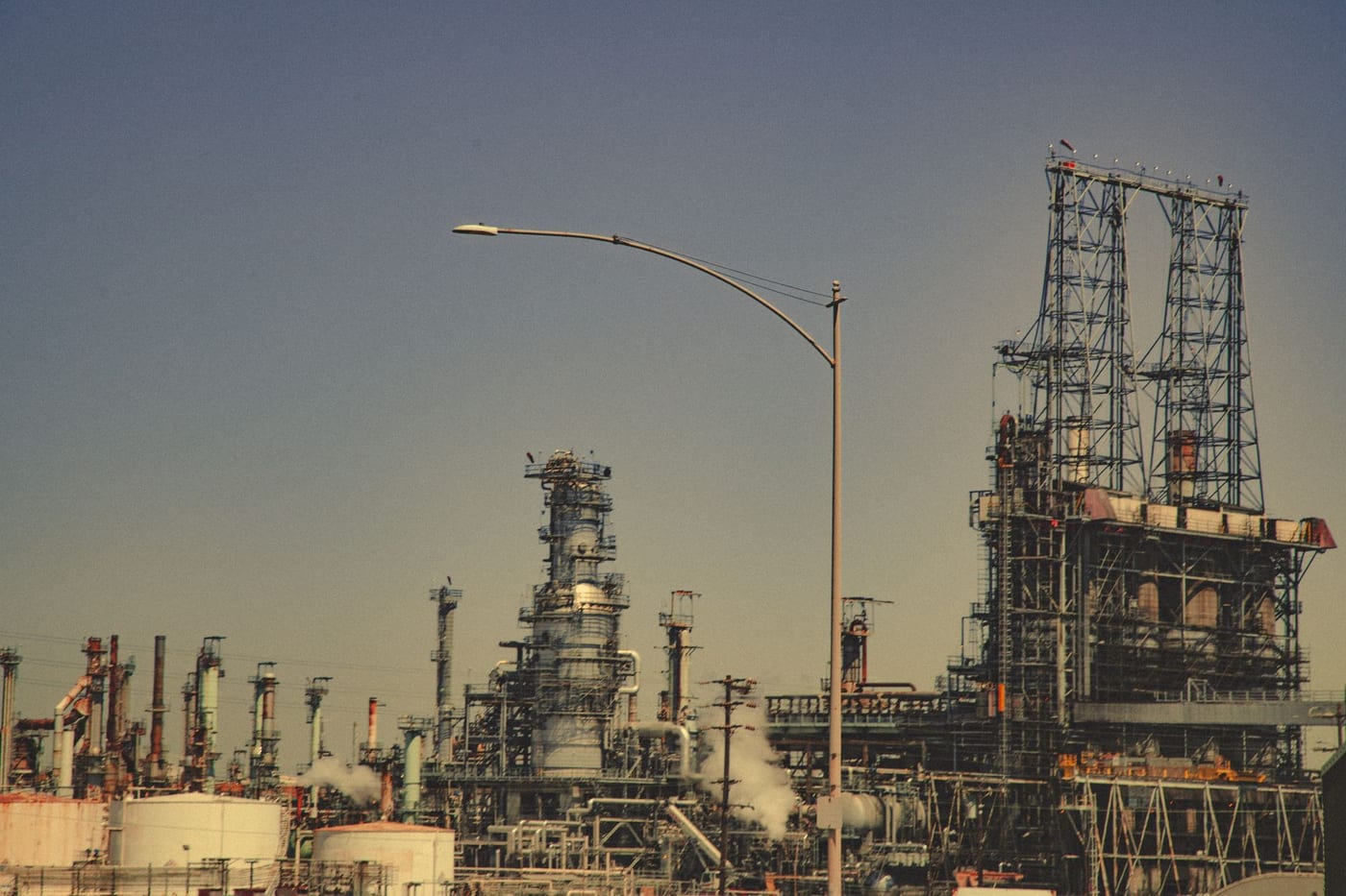 A refinery's pipework and towers against a clear sky