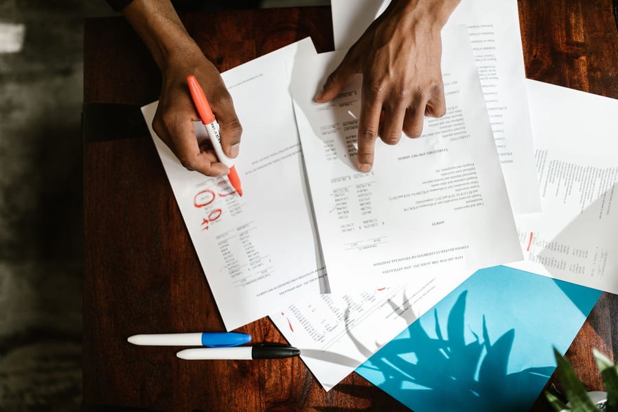 Hands marking up figures on a printed financial statement