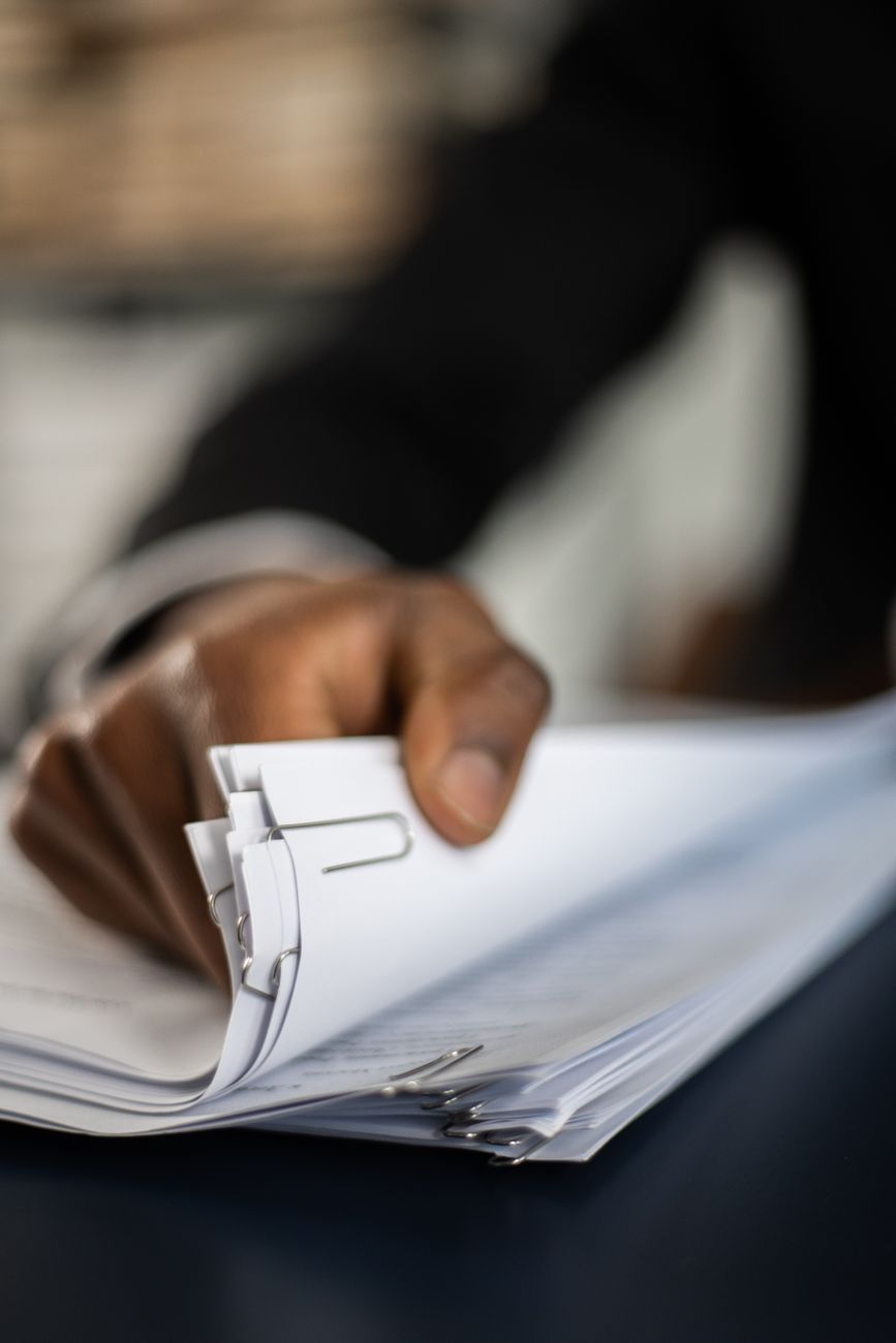 A hand organising a stack of documents with paper clips