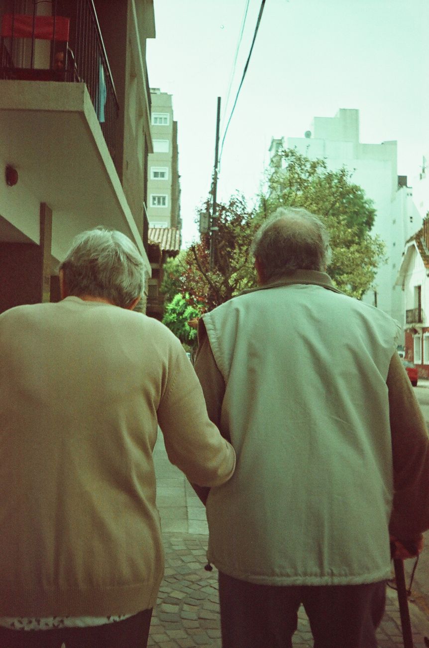 An older couple walking hand in hand through their neighbourhood