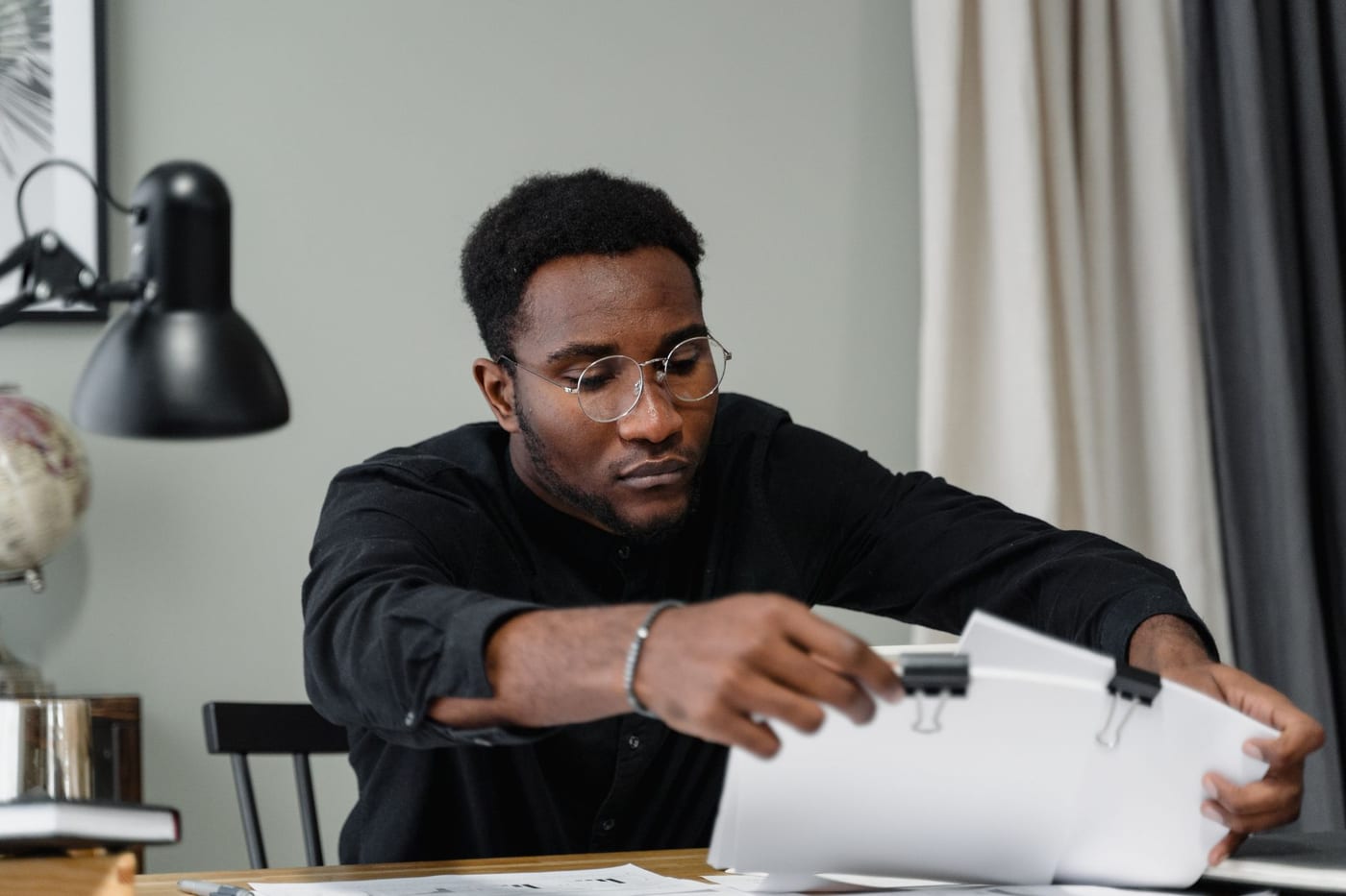 A man in glasses concentrating on a printed document
