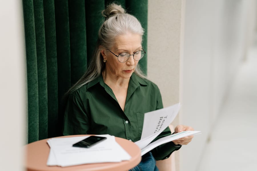 An older woman reading through papers at a small table
